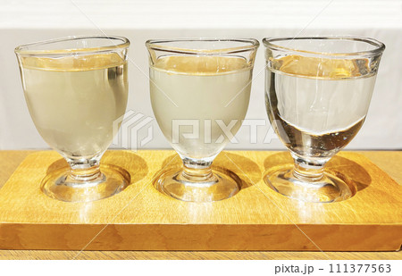 ガラスのお猪口に入った日本酒を飲み比べ 111377563