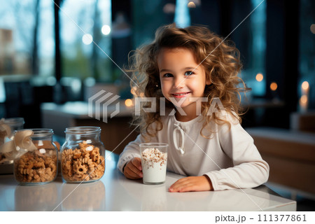 Child girl is sitting at the table and having dinner with yogurt with granola, grain cookies in the kitchen 111377861