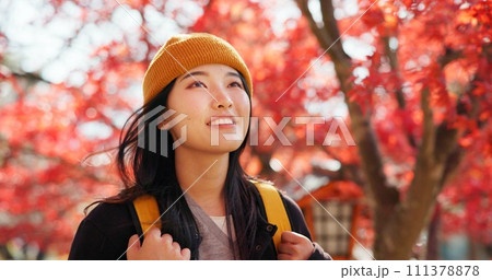 Japanese, woman and travel with autumn nature, trees and red leaves in Kyoto forest with happiness. Girl, smile and walk in park, woods with orange environment or adventure in colorful zen garden 111378878