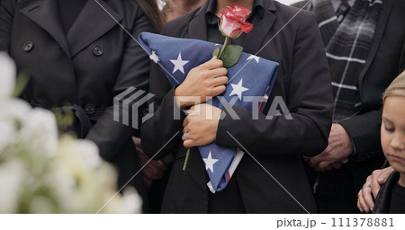 Funeral, graveyard and woman with American flag for veteran for respect, ceremony and memorial service. Family, depression and sad people with flower in cemetery for military, army and soldier hero 111378881