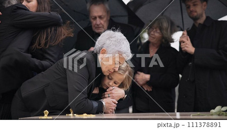 Funeral, crying family and child hug grandmother for support, mourning depression and death at emotional burial event. Dead, love and kid hugging senior woman, grandma and grief at farewell ceremony 111378891