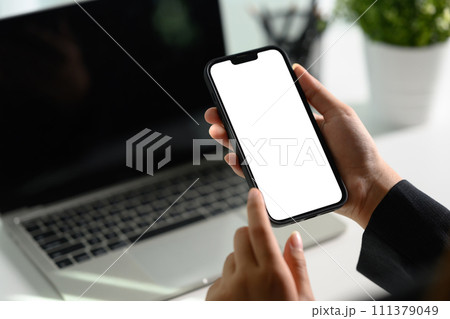 Unrecognizable businesswoman using smartphone at office desk0 Empty screen for your text message 111379049