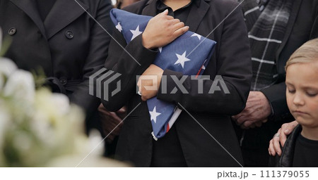 Funeral, cemetery and woman with American flag for veteran for respect, ceremony and memorial service. Family, depression and sad people by coffin in graveyard for military, army and soldier mourning 111379055