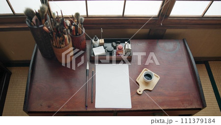 Art, paint brush and painting tool for painter, calligraphy and drawing at a desk for creative work. Sketch paper, Japanese sumi and home studio with ink pot and document for creativity above 111379184