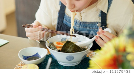 Hungry woman, eating ramen and restaurant with chopsticks, noodles and lunch for nutrition. Girl, person and meal for health, wellness and diet for wellness at cafeteria, diner and brunch in Tokyo 111379452