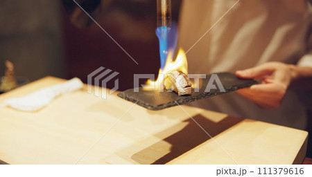 Hands, fire and cooking sushi with chef in restaurant for traditional Japanese food or cuisine closeup. Kitchen, flame for seafood preparation and person working with gourmet meal recipe ingredients Hands, fire and cooking sushi with chef in restaurant for traditional Japanese food or cuisine closeup. Kitchen, flame for seafood preparation and person working with gourmet meal recipe ingredients 111379616