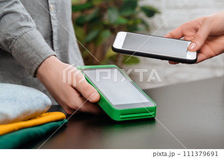 Contactless payment with smartphone and nfc terminal in clothes shop 111379691