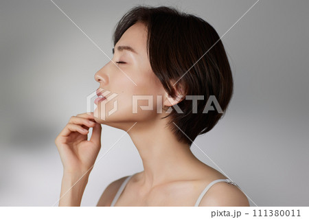 光と影の背景で撮影をした若い女性のスキンケアイメージ 111380011