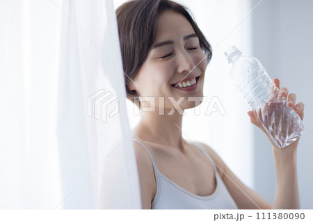 水を飲んでリラックスする若い女性 111380090