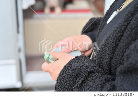 冬のキャンピングカー旅行　ハンドウォーマー（充電式カイロ）で手を温める若い女性 111380187