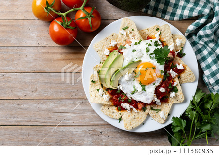 Traditional Mexican chilaquiles breakfast on wooden table Traditional Mexican chilaquiles breakfast on wooden table 111380935