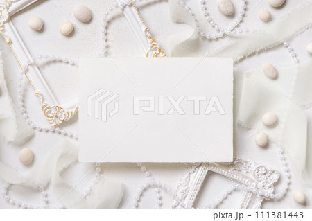 Blank card near white decorations, pebbles and silk ribbons top view, wedding menu mockup Blank card near white decorations, pebbles and silk ribbons top view, wedding menu mockup 111381443