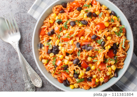 Spicy vegetarian side dish tomato rice with black beans, onions and corn close-up in a bowl. Horizontal top view 111381804