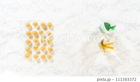 Flat lay. Dipping dough balls into green melted chocolate to make cactus cake pops for the Cinco de Mayo celebration. Flat lay. Dipping dough balls into green melted chocolate to make cactus cake pops for the Cinco de Mayo celebration. 111383372