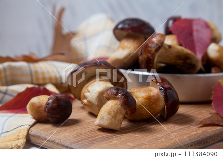 Several Imleria Badia or Boletus badius mushrooms commonly known as the bay bolete and vintage pan with mushrooms on wooden cutting board.. 111384090