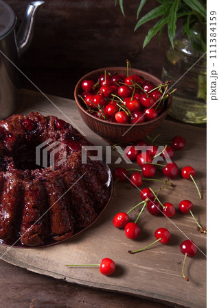 Delicious chocolate cake with sweet cherry on dark wooden background.. Delicious chocolate cake with sweet cherry on dark wooden background.. 111384159