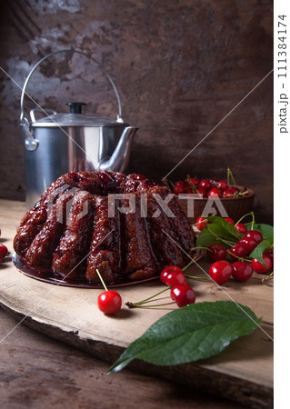 Delicious chocolate cake with sweet cherry and vintage kettle on dark wooden background.. 111384174
