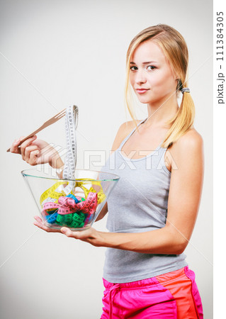 Diet. Girl with colorful measuring tapes in bowl 111384305