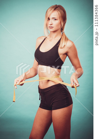 Fitness girl measuring her waistline Fitness girl measuring her waistline 111384366