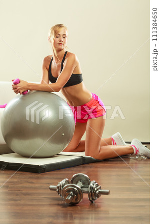 Woman with gym ball and dumbbell doing exercise Woman with gym ball and dumbbell doing exercise 111384650