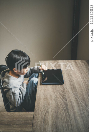部屋でタブレットをいじっている子ども 部屋でタブレットをいじっている子ども 111385018