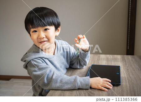 タブレットとタッチペンで勉強するカメラ目線の子ども 111385366