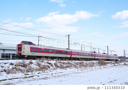 雪の積もった田園の土手を走る標準ゆったりやくも色の381系特急やくも号 111388310