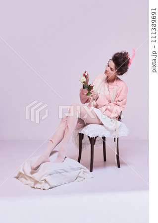 Beautiful young woman sitting on chair and painting white rose flower with red nail polish. Making life brighter, giving more passion. Beautiful young woman sitting on chair and painting white rose flower with red nail polish. Making life brighter, giving more passion. 111389691