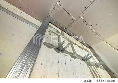 Unfinished brick wall in a room under construction prepared for drywall plates frame installation. 111390606