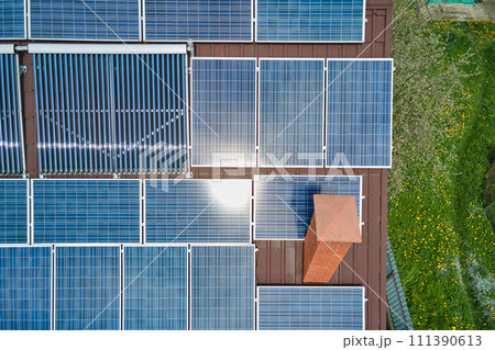 Building roof with rows of blue photovoltaic panels and vacuum air solar collectors for water heating and producing clean ecological electricity. Renewable electric and heat energy with zero emission 111390613