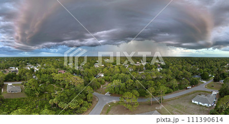 Landscape of dark ominous clouds forming on stormy sky during heavy thunderstorm over rural town area at sunset 111390614