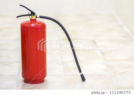 Fire extinguisher bright red isolated on white light tiles walls and floor copy space background. Danger and safety, fire protection concept. Fire extinguisher bright red isolated on white light tiles walls and floor copy space background. Danger and safety, fire protection concept. 111390773