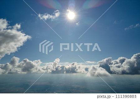 Aerial view from airplane window at high altitude of earth covered with white puffy cumulus clouds 111390803