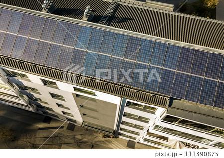 Aerial view of solar photovoltaic panels on a roof top of residential building block for producing clean electric energy. Autonomous housing concept. Aerial view of solar photovoltaic panels on a roof top of residential building block for producing clean electric energy. Autonomous housing concept. 111390875