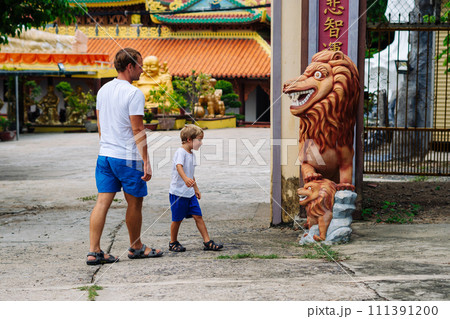 Father and son tourists walking in Vietnam Buddhist Temple, happy childhood, exploring world Father and son tourists walking in Vietnam Buddhist Temple, happy childhood, exploring world 111391200