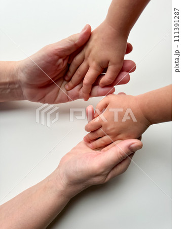 Womans gesture with child's hand on white surface Womans gesture with child's hand on white surface 111391287