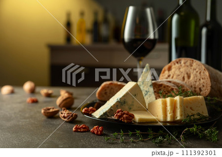 Cheese, bread, red wine, and walnuts on a kitchen table. 111392301