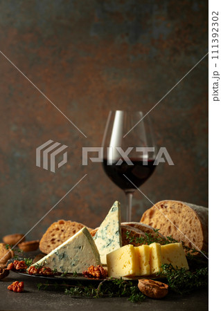 Cheese, bread, red wine, and walnuts on a stone table. 111392302