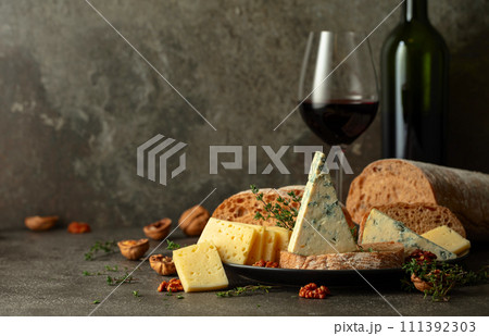 Cheese, bread, red wine, and walnuts on a kitchen table. 111392303
