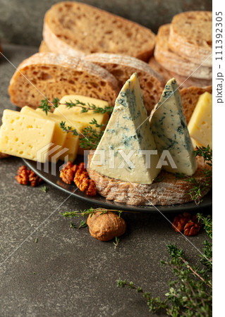 Cheese, bread, walnuts, and thyme on a stone kitchen table. 111392305