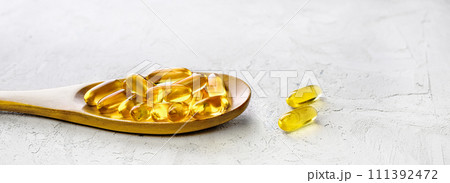 Omega 3 capsules in wooden spoon on shabby concrete background Omega 3 capsules in wooden spoon on shabby concrete background 111392472