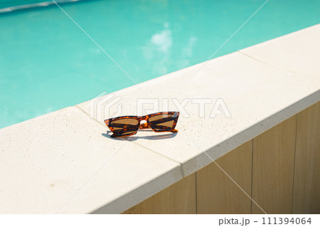 Summer holidays, travel and vacation concept. Brown funky sun glasses near swimming pool. Outdoor shot Summer holidays, travel and vacation concept. Brown funky sun glasses near swimming pool. Outdoor shot 111394064