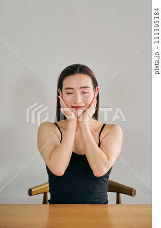 両手で顔をマッサージして肌のお手入れをする30代女性 111395184