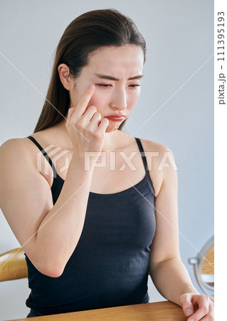 鏡を見ながら肌のシワを気にする30代女性 111395193