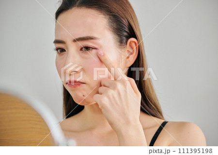 鏡を見ながら肌のシワを気にする30代女性 111395198