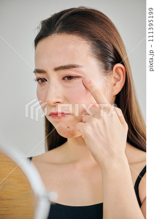 鏡を見ながら肌のシワを気にする30代女性 鏡を見ながら肌のシワを気にする30代女性 111395199