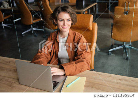 Portrait of woman working in office, sitting at table with laptop, girl programmer coding in co-working space, doing her job at workplace 111395914