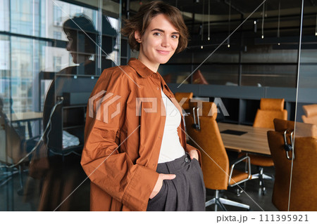 Portrait of confident young businesswoman, digital nomad posing in her office, wearing casual clothes and smiling Portrait of confident young businesswoman, digital nomad posing in her office, wearing casual clothes and smiling 111395921