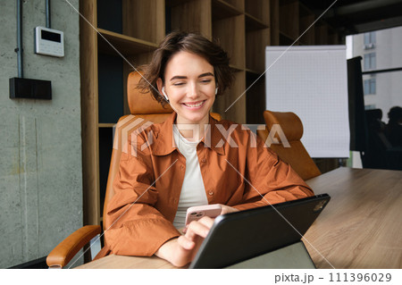Portrait of woman in office, employee working on project with digital tablet, using device on meeting in conference room Portrait of woman in office, employee working on project with digital tablet, using device on meeting in conference room 111396029