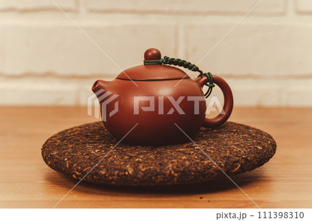 Yixing clay teapot for tea brewing, accompanied by pressed pu-erh black tea disc 111398310